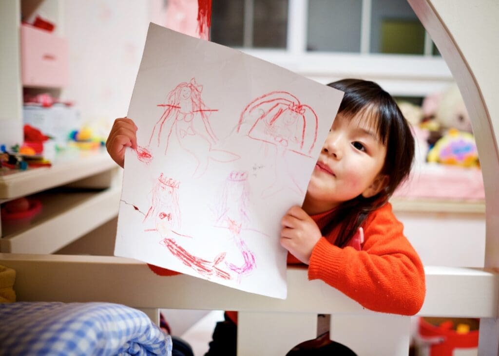 A child at a daycare holding up a drawing that they made